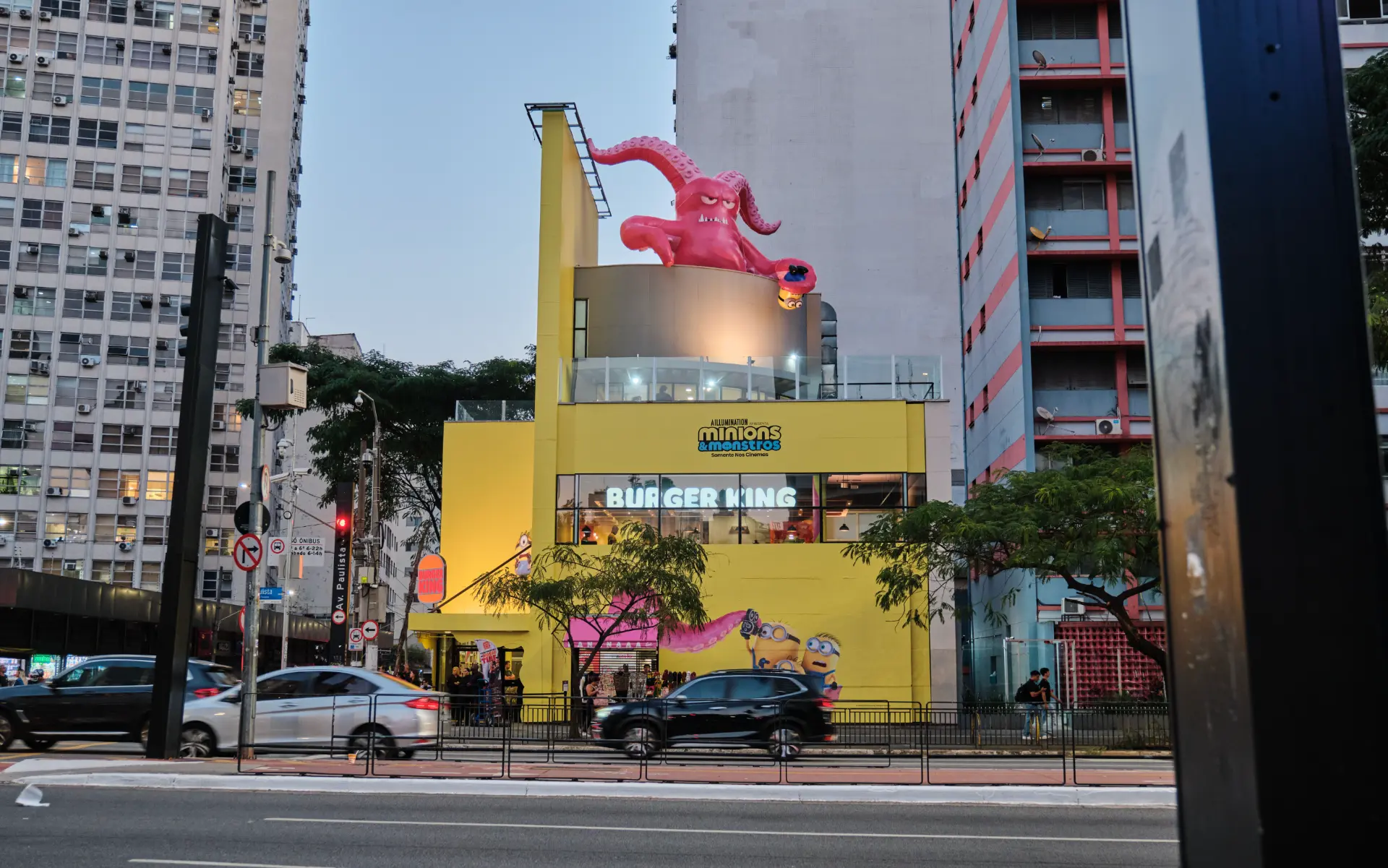 Fachada do Burger King Paulista com polvo inflável de Minions e Monstros ao anoitecer