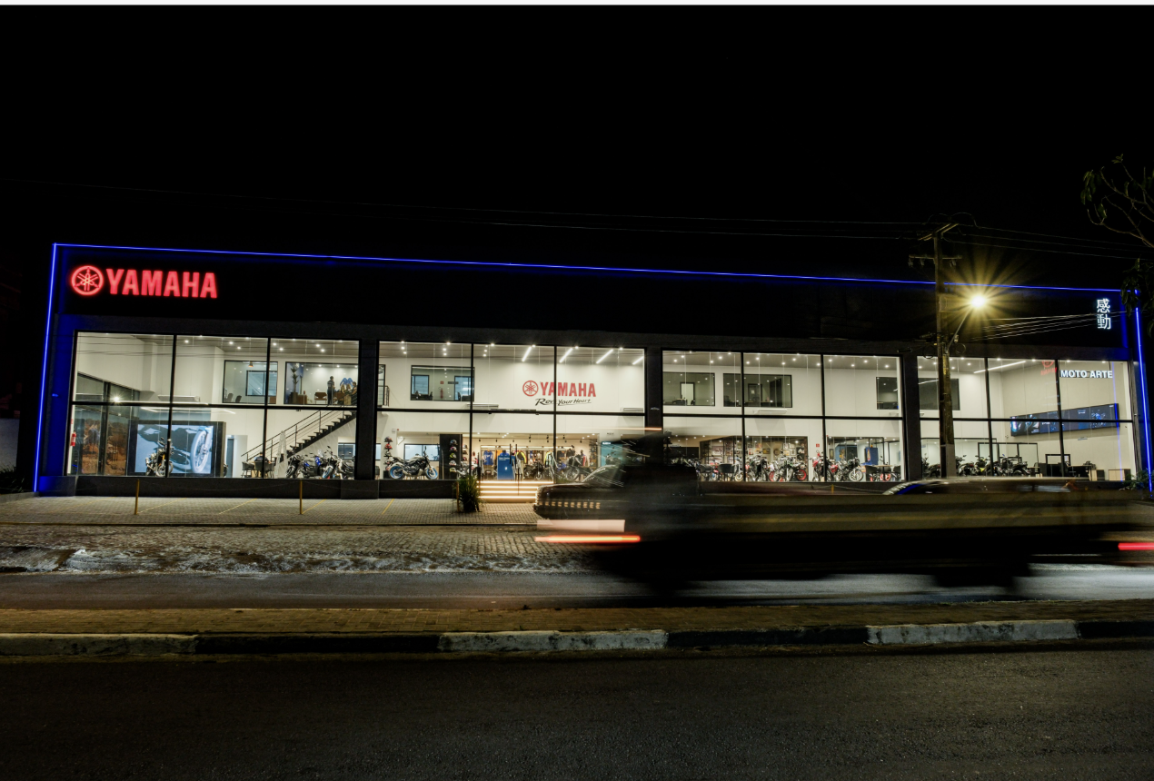 Fachada noturna da loja conceito Yamaha em Caruaru, com letreiro vermelho iluminado e contorno de LED azul