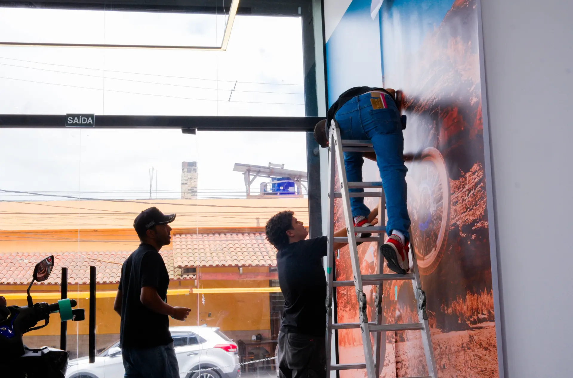 Instalação de grande painel fotográfico de moto em paredão próximo à entrada da loja